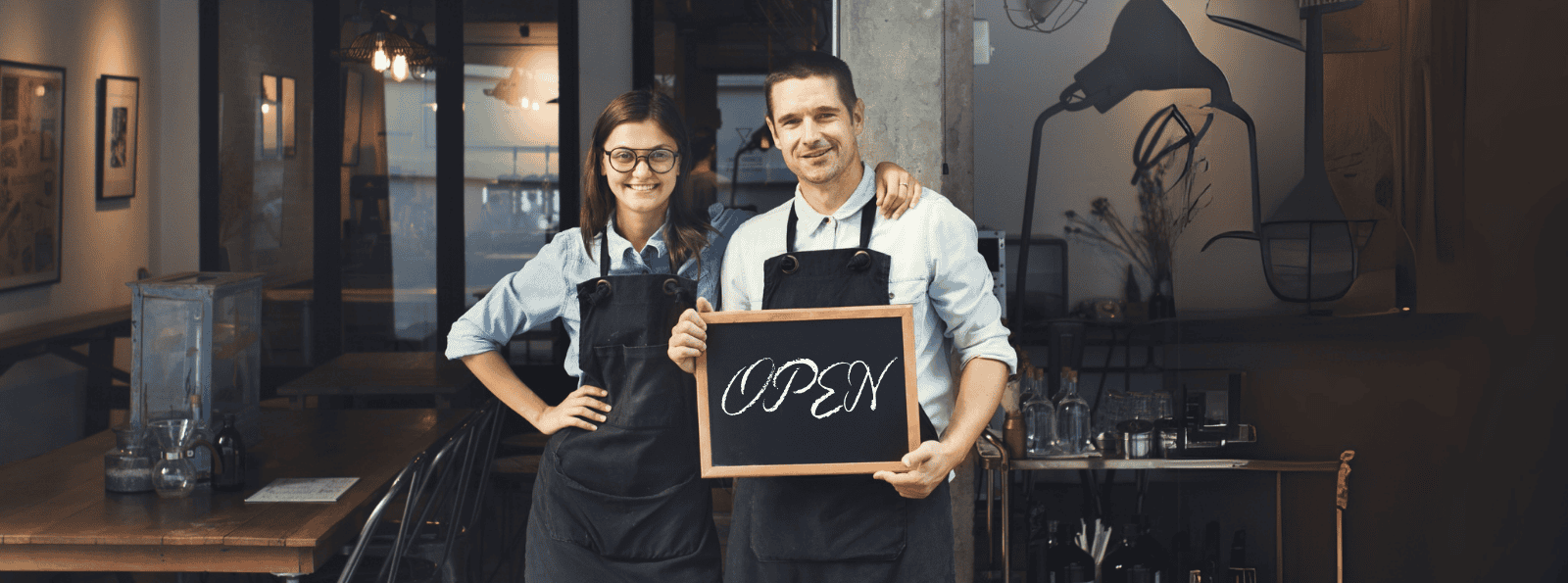 Small Business owner standing in front of their business with an open sign