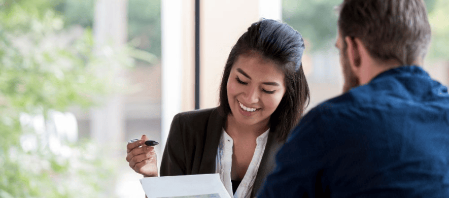 A man and woman at a table with papers, engaged in a discussion about Commercial Loans.
