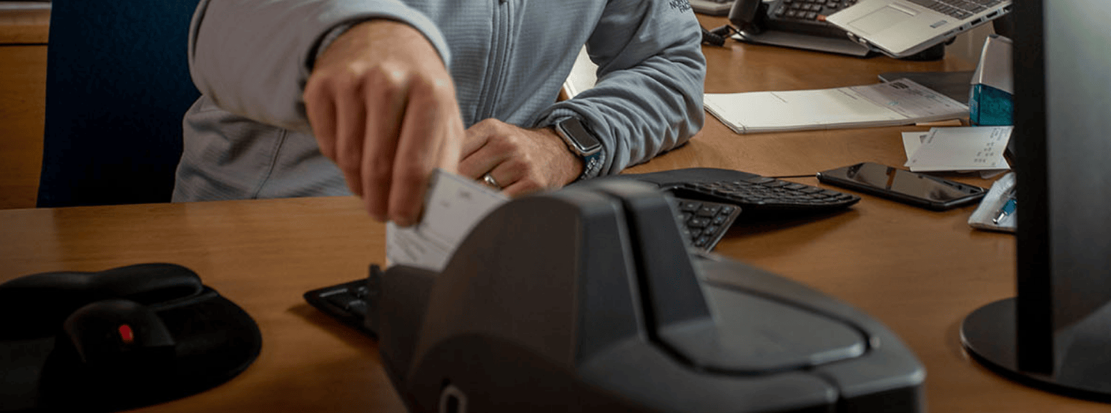 Man putting check into scanner at his desk