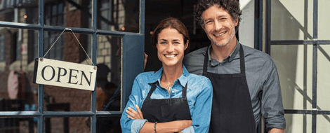 A man and woman stand in front of a business, considering SBA loans for their venture